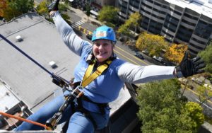 Cheryl smiles as she repels off a building.