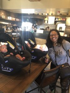 Latia smiling with her adorable baby girls in a coffee shop.