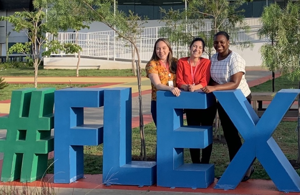 Daija stands with two of her peers outside behind a sculpture spelling out "#FLEX"
