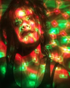Emily's mentor Jodi on a Webex call with a disco ball of green, red, and orange lights surrounding her.