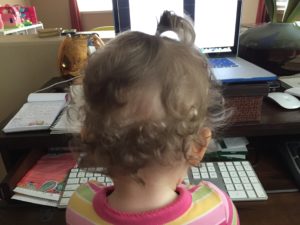 Photographed from behind, Carlene's daughter sits at her desk pretending to type away at the keyboard.