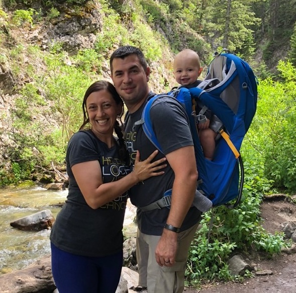 Chantal and her family smile while hiking next to a creek in the woods.