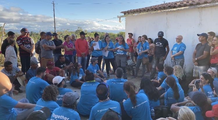 The entire group of volunteers sitting and standing in a circle celebrating a successful build.