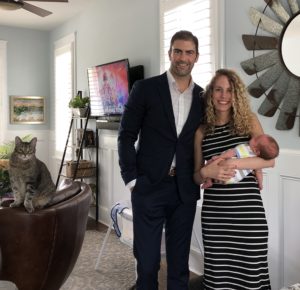Dustin standing with his now wife, baby, and cat.