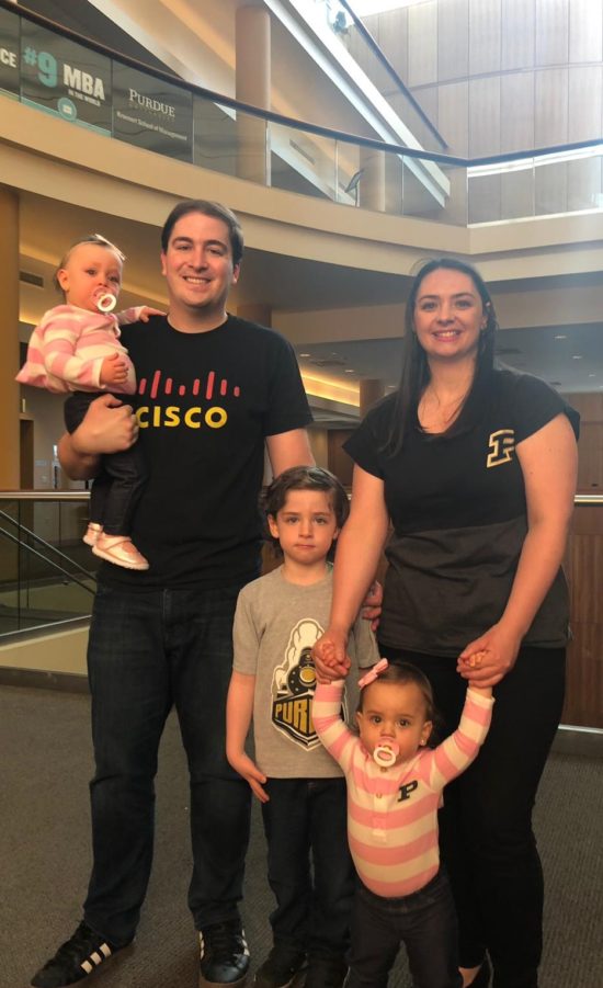 Andrew standing in a Cisco shirt with his wife, son, and two daughters at Purdue University.