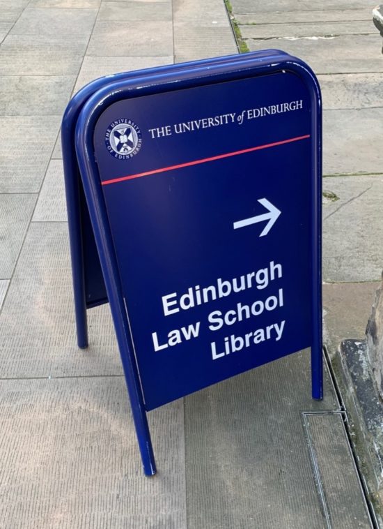 A dark blue sign pointing towards the Edinburg Law School Library
