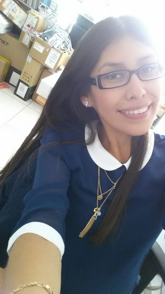 Yaritza smiling in front of boxes of tech equipment at her second job after graduating. 