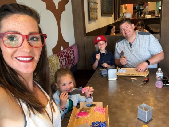 Jeane, wearing red glasses, smiles with her family.