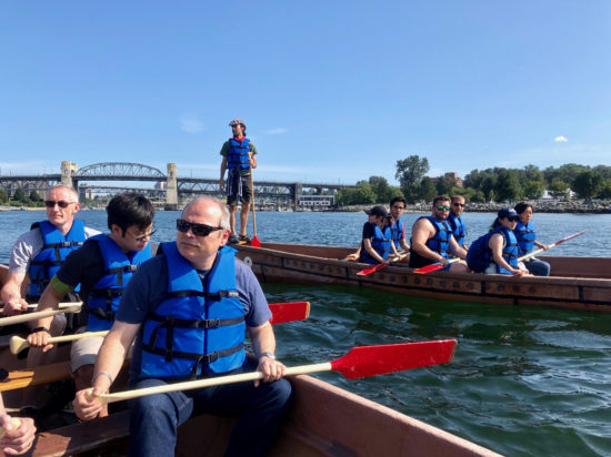 Sang's peers sitting in kayaks holding oars on a river