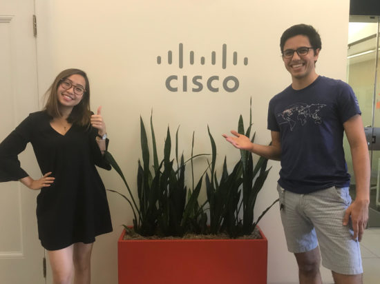 Sang does a "thumbs-up" pose with a peer in front of a Cisco sign.