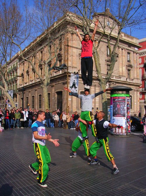 Barcelona, Catalonia, Spain - February 16, 2008: street performers along the Rambla. A group of acrobats put on a show of their gymnastic skills and balance to the music creating a crowd of curious tourists around. After the performance some of them passed among those present to collect a few coins