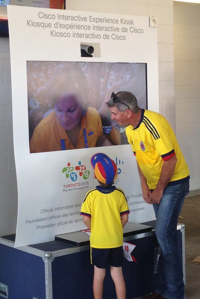Colombia fans speak with a TO2015 volunteer through Cisco TelePresence before the women's Gold-medal soccer game.